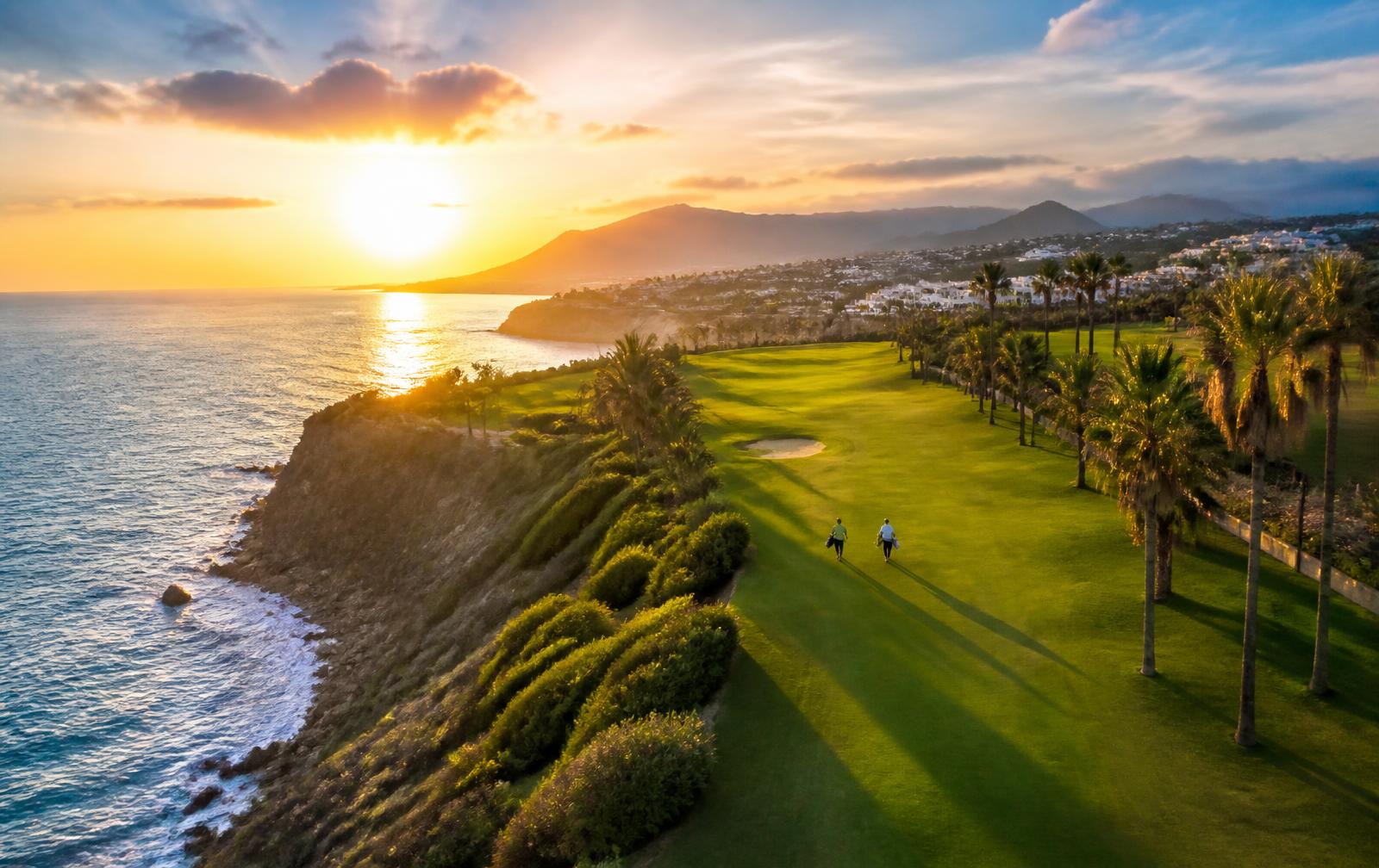 Coastal golf course at sunset with golfers walking the fairway